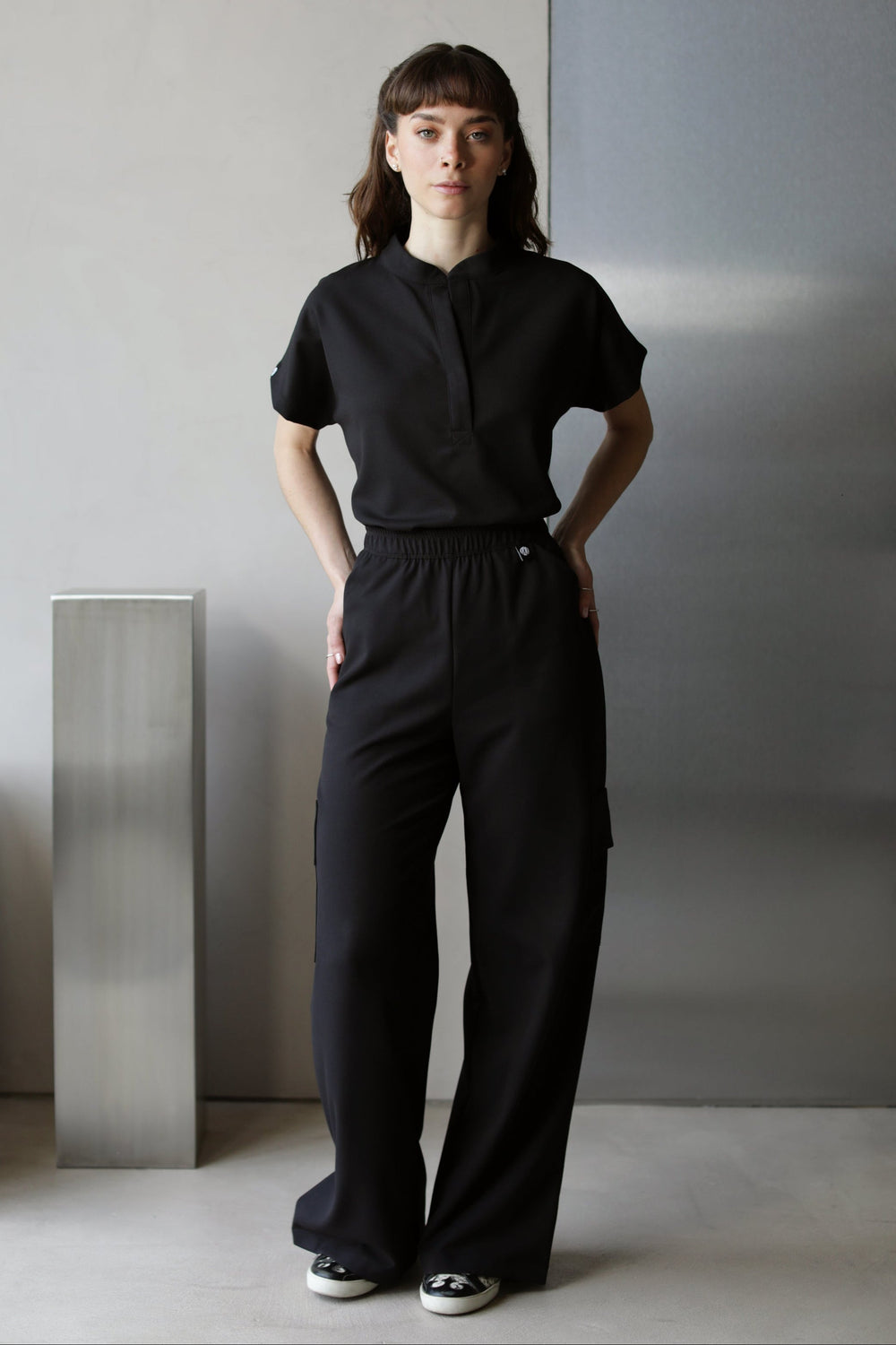 Model wearing Glam Black Scrub Top with matching scrub pants