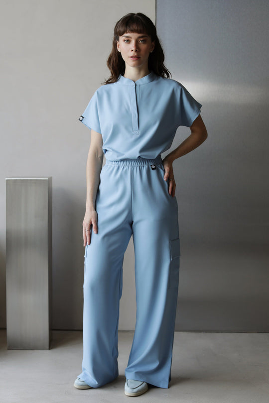 Model wearing Glam Dream Blue Scrub Top with matching Dream Blue scrub pants