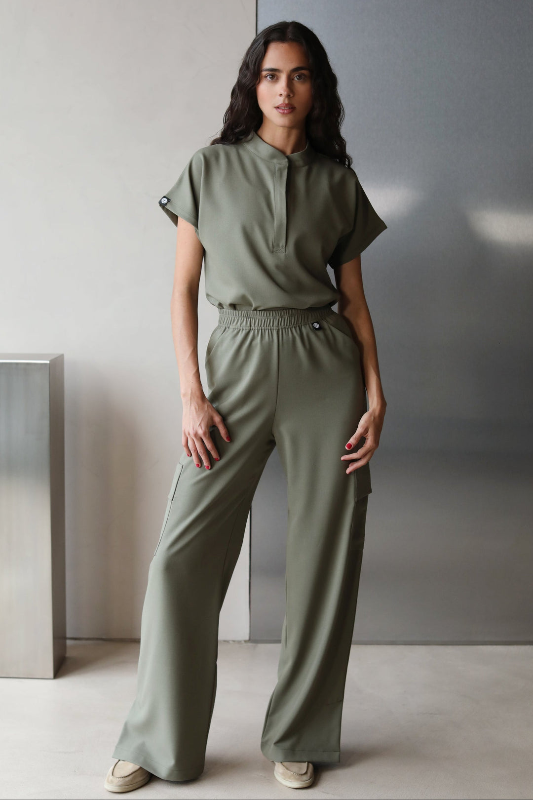 Model wearing Glam Olive Scrub Top with matching scrub pants