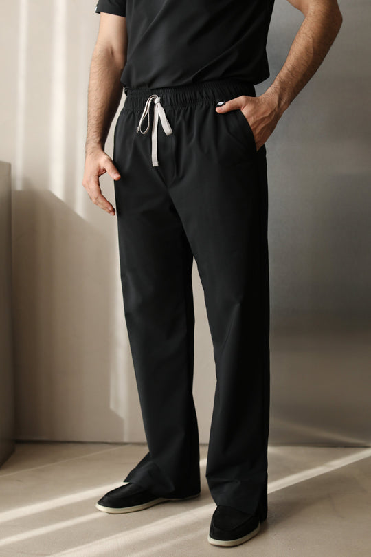 Front view of a man wearing Harry Black W&amp;C Shield™ scrub pants, highlighting the straight-leg fit, drawstring waistband, and side pockets.