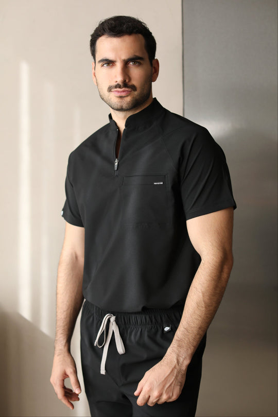 Man wearing the Harry Black W&amp;C Shield™ scrub top and black scrub pants, shown in a front-facing three-quarter view.