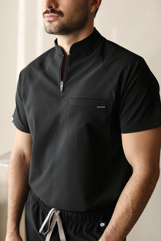 Close-up of a man wearing the Harry Black W&amp;C Shield™ scrub top, highlighting the high collar, front zipper, and chest pocket.