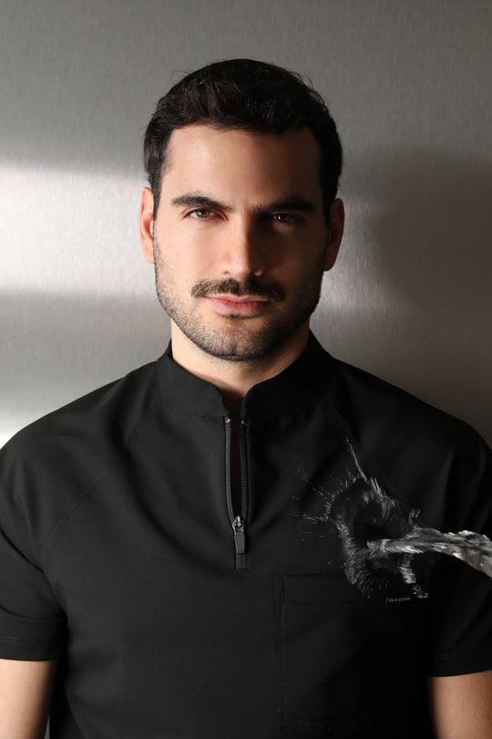 Close-up portrait of a man wearing the Harry Black W&amp;C Shield™ scrub top during a water-repellency demonstration.