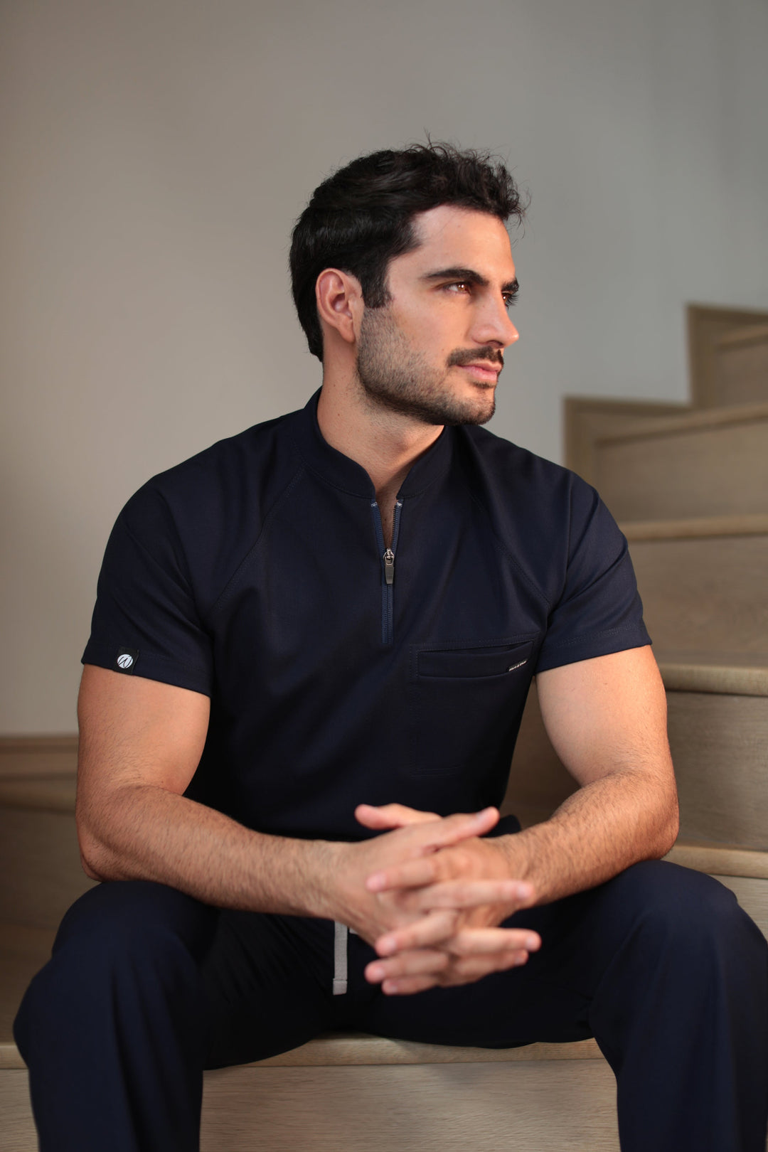 Man wearing Harry Navy Scrub Top in a seated position