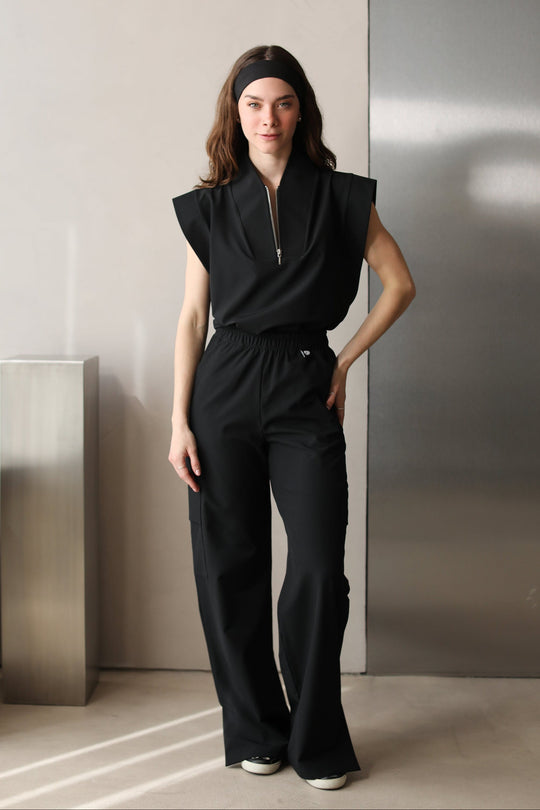 Full-body front view of a woman wearing Kate Black W&amp;C Shield™ scrub pants with the matching Kate Black scrub top.