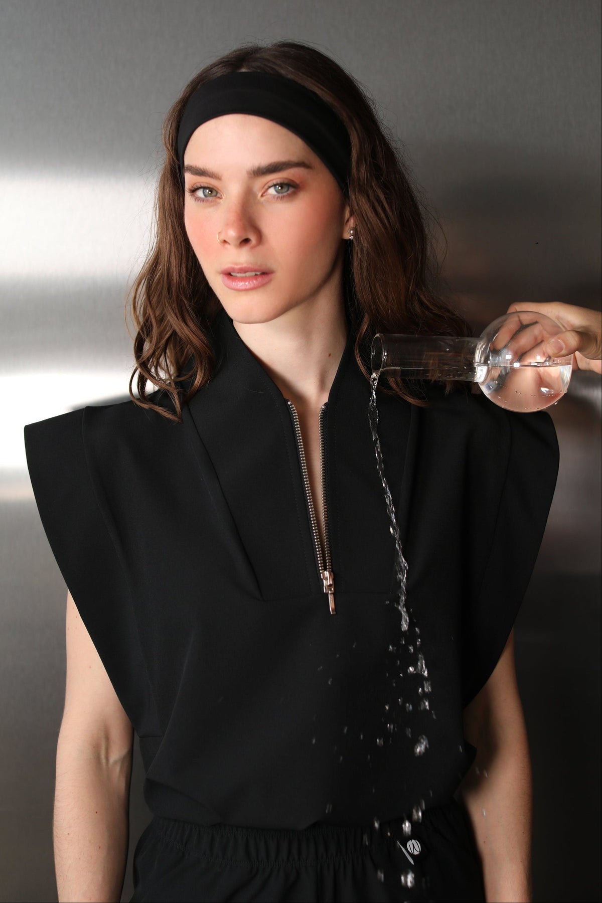 Woman wearing the Kate Black W&C Shield™ scrub top while clear liquid is poured over the shoulder and front of the fabric.
