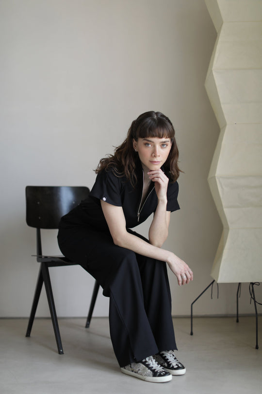 Model seated wearing Victory Black Scrub Top with matching scrub pants