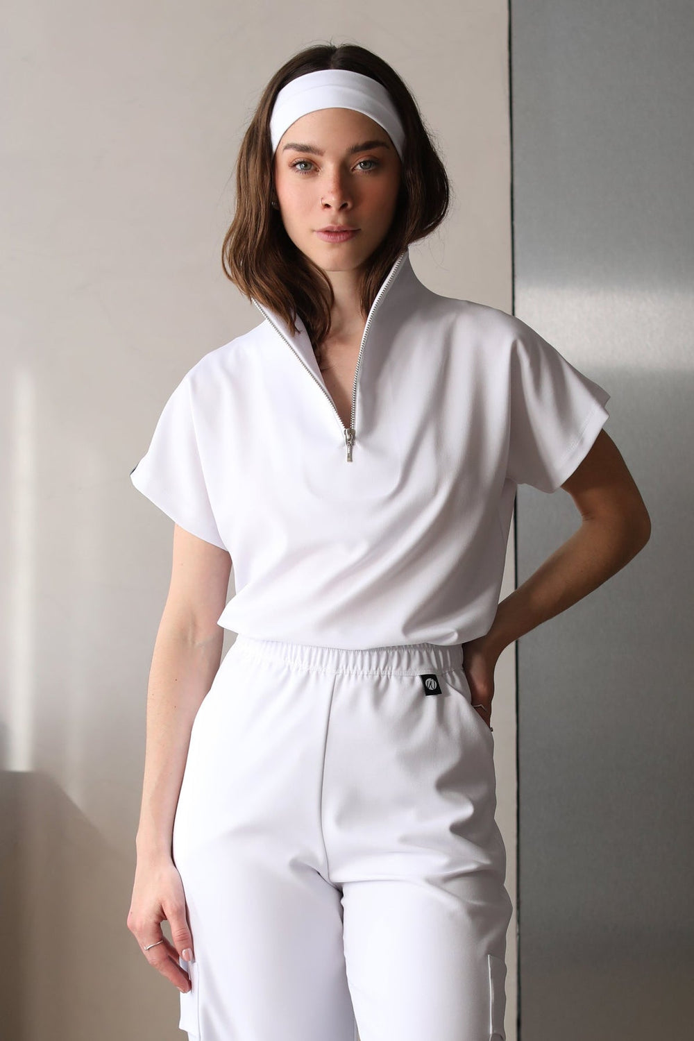 Model wearing Victory Crystal White Scrub Top with matching scrub pants