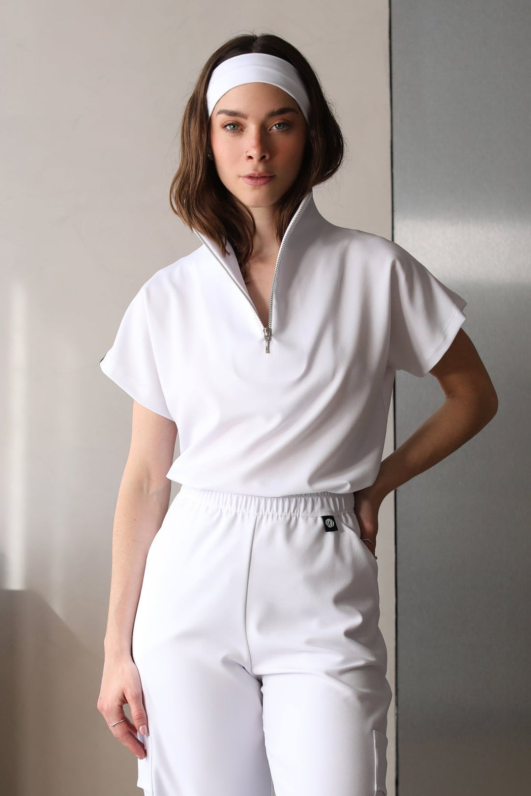 Model wearing Victory Crystal White Scrub Top with matching scrub pants