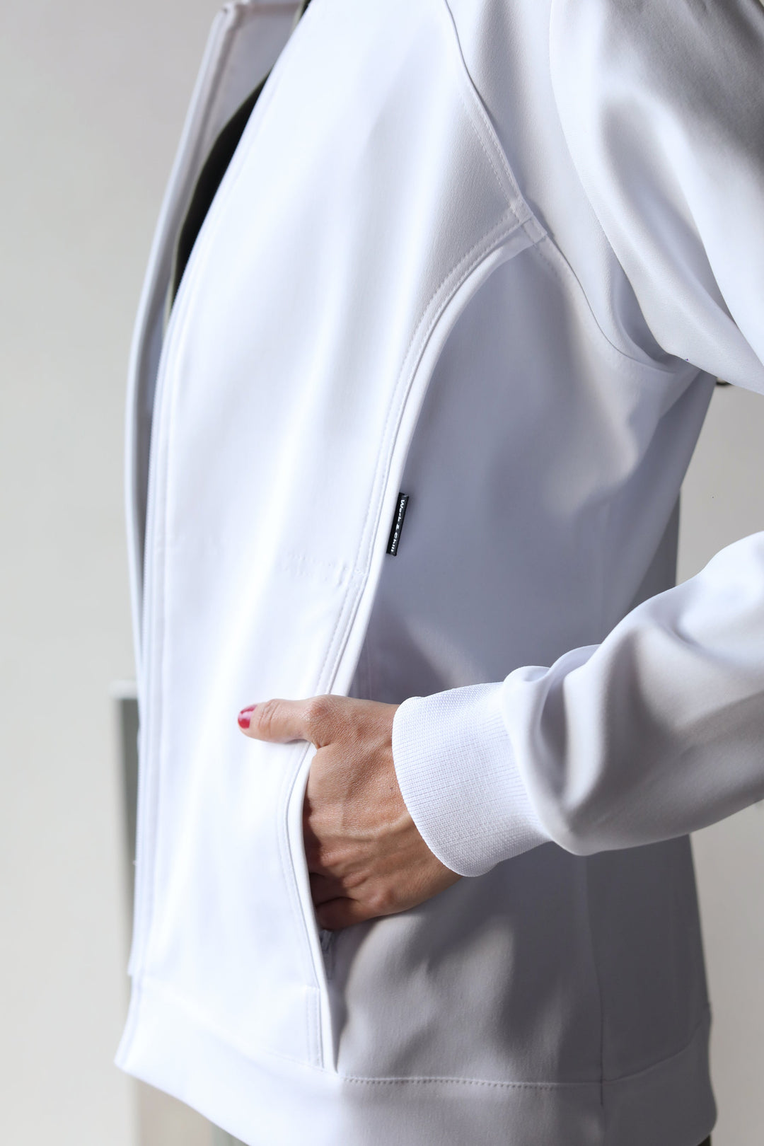 Healthcare professional wearing Women’s White Medic Coat over green scrubs